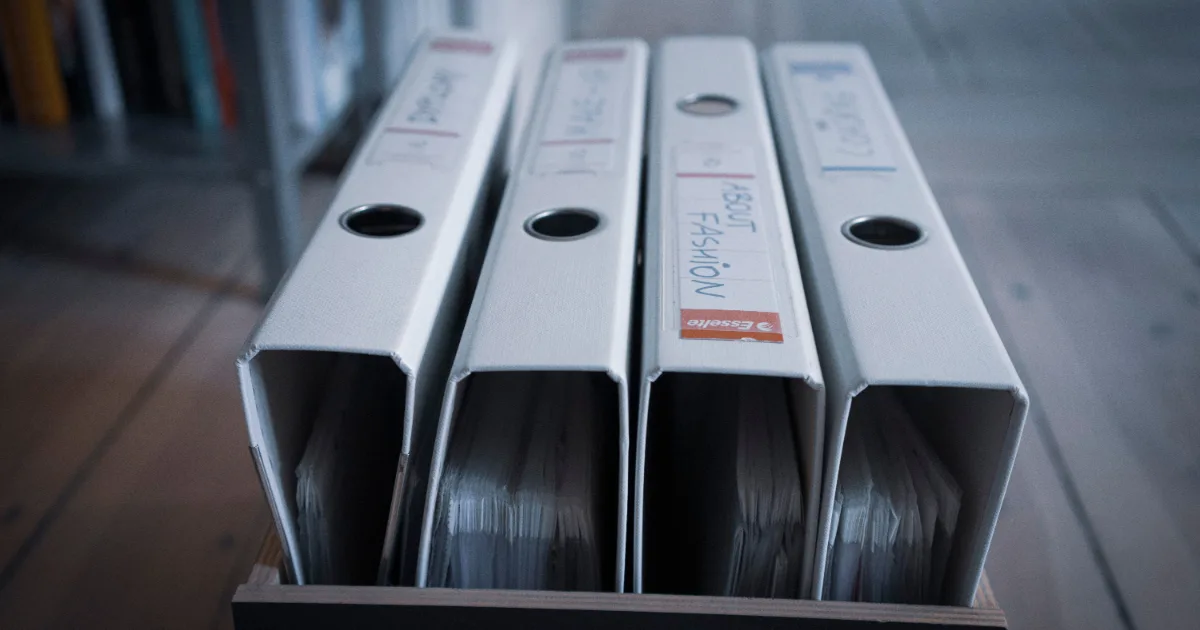 Stack of paperwork and reading glasses on an office desk representing HUD staffing shortages and Section 8 application processing backlogs