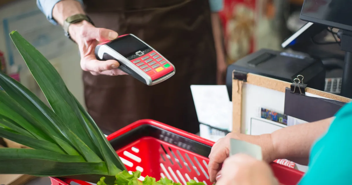 Customer using an EBT card to pay for groceries at a supermarket checkout POS terminal