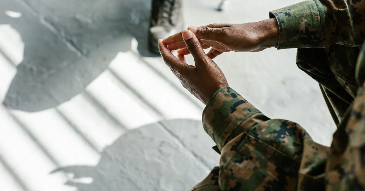 US service member in camouflage uniform resting hands while making a decision, representing Montgomery GI Bill vs Post-9/11 GI Bill comparison